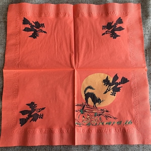 May include: Orange paper napkins with a Halloween theme. The napkins feature black silhouettes of witches flying on broomsticks, black cats, and pumpkins.
