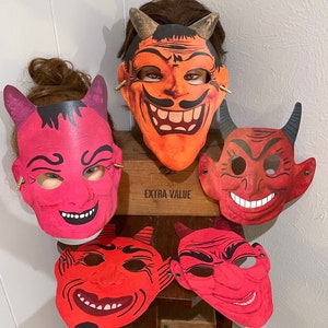 Puede incluir: Cuatro máscaras de diablo rojas y naranjas con cuernos. Las máscaras tienen diferentes expresiones faciales y están hechas de papel.