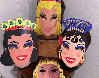 May include: Four vintage paper Halloween masks with colorful designs. The masks feature a queen, a princess, a woman with a crown, and a woman with a blue and gold headdress.