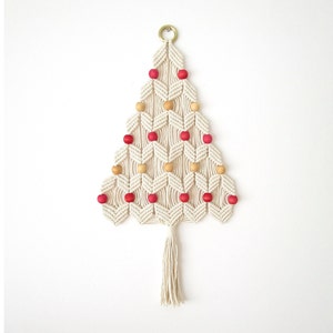 May include: A white macrame Christmas tree wall hanging with red and brown wooden beads.