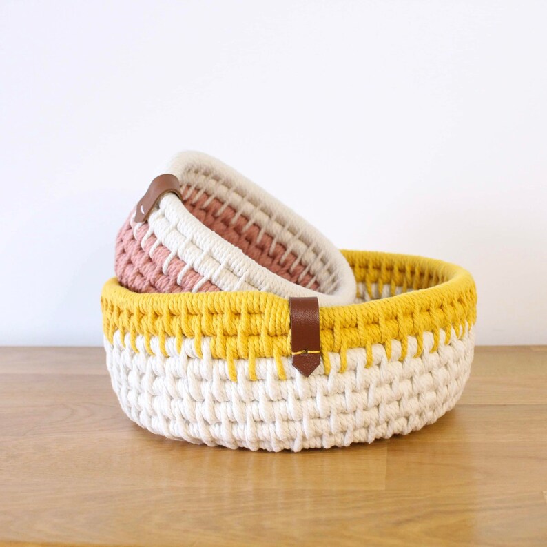 Deux corbeilles de rangement de couleurs différentes, réaliséee avec de la corde écrue, rose et jaune.