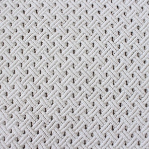 May include: White macrame wall hanging with a diamond pattern.