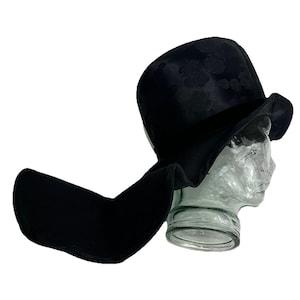 May include: A black wide-brimmed hat with a floral pattern. The hat has a long flap that can be worn down or up.