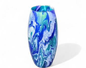 May include: An oval-shaped vase with a vibrant, abstract design. The vase features a blend of blues and greens, creating a marbled effect. The colors swirl and flow, adding visual interest. The vase is a decorative item.