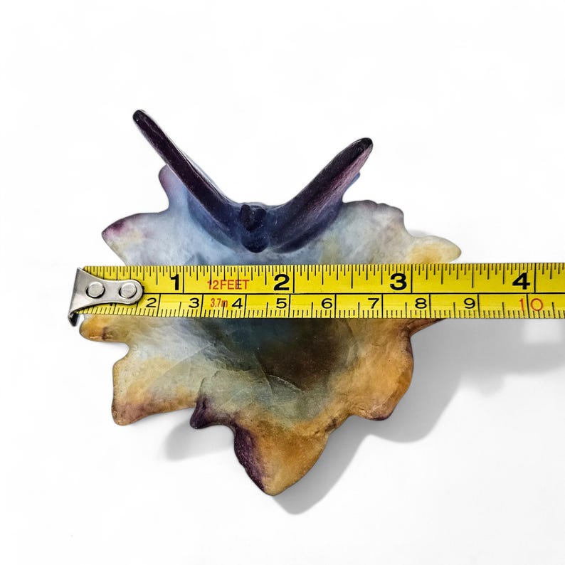 May include: A blue and purple ceramic leaf-shaped dish with a raised center. The dish is approximately 4 inches wide.