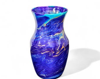 May include: A blue and purple glass vase with a swirling, marbled design. The vase has a wide mouth and a narrow base.