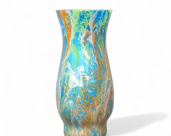 May include: A decorative vase with a unique, swirled paint design. The colors include shades of blue, green, orange, and white, creating a marbled effect. The vase has a wide base, a slender neck, and a flared top.