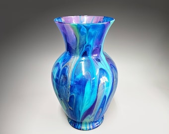 May include: A blue, purple, and green glass vase with a swirling, abstract design. The vase is made of glass and has a smooth, glossy finish.