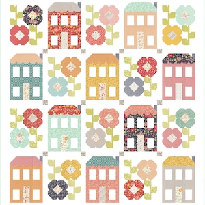 Puede incluir: Un edredón de retazos con casas y flores coloridas. Las casas son de varios colores, incluyendo rojo, azul y amarillo, con tejados estampados y ventanas blancas. Las flores son en tonos de rojo, rosa y amarillo, con tallos y hojas verdes.