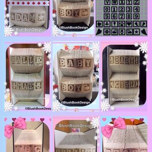 May include: A collection of book folding art pieces, each featuring a different name or phrase. The pieces are made from folded pages of books, and they are displayed on a white background. The names include "CANADA DAY", "BABY BOY", "HALLE & MAC", "BABY GIRL", "ABC", "WILLIED", and "UZOE".