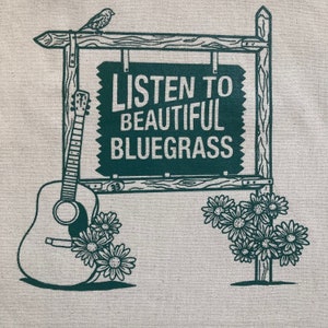May include: A green and white sign with the text "Listen to Beautiful Bluegrass" on it. A guitar and flowers are on either side of the sign.