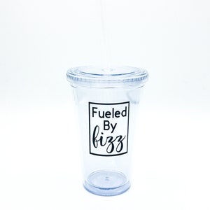May include: A clear plastic tumbler with a black lid and a black straw. The tumbler has a black vinyl decal that says "Fueled By Fizz".