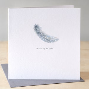 Une carte avec une plume bleue en pensant à vous. Carte de sympathie. Conception de plumes flottantes. Carte de rétablissement. Votre carte vous manque.