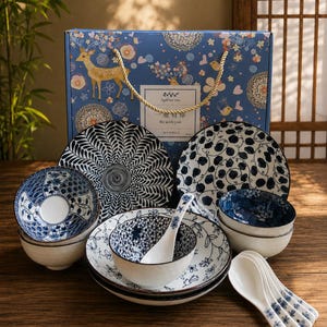 May include: A ceramic dinnerware set featuring blue and white patterns, including bowls, plates, and spoons. The set is presented in a blue gift box decorated with deer and floral illustrations, with the text "A gift for you" and "Be with you."