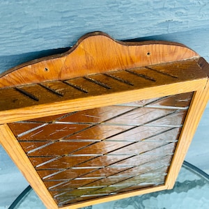 May include: A wooden knife holder with a diamond pattern on the front. The holder has a brown stain and is made of wood.