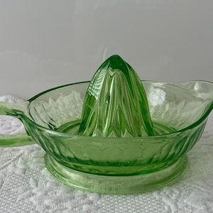 Peut inclure: Presse-agrumes vintage en verre vert clair. Il comprend un presse-agrumes conique et un bol avec une poignée et un bec verseur. Le presse-agrumes est en verre pressé avec un motif décoratif.