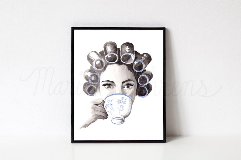 Watercolor portrait featuring a grayscale woman with blue curlers in her hair sipping from a blue and white floral teacup. Art print is displayed in a black picture frame on a white background.