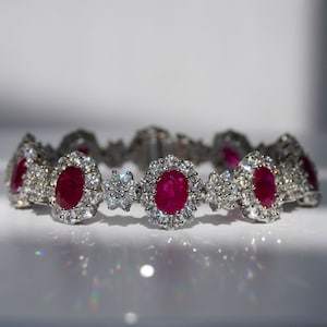 以下が含まれることがあります： ダイヤモンドで囲まれた楕円形のルビーの宝石が並んだシルバーブレスレット