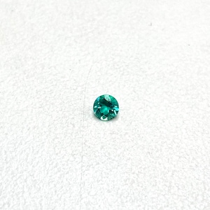 May include: A round, faceted gemstone with a vibrant teal color. The gem is set against a white background, showcasing its brilliance. The gemstone's facets reflect light, creating a sparkling effect. This gemstone is suitable for jewelry making.