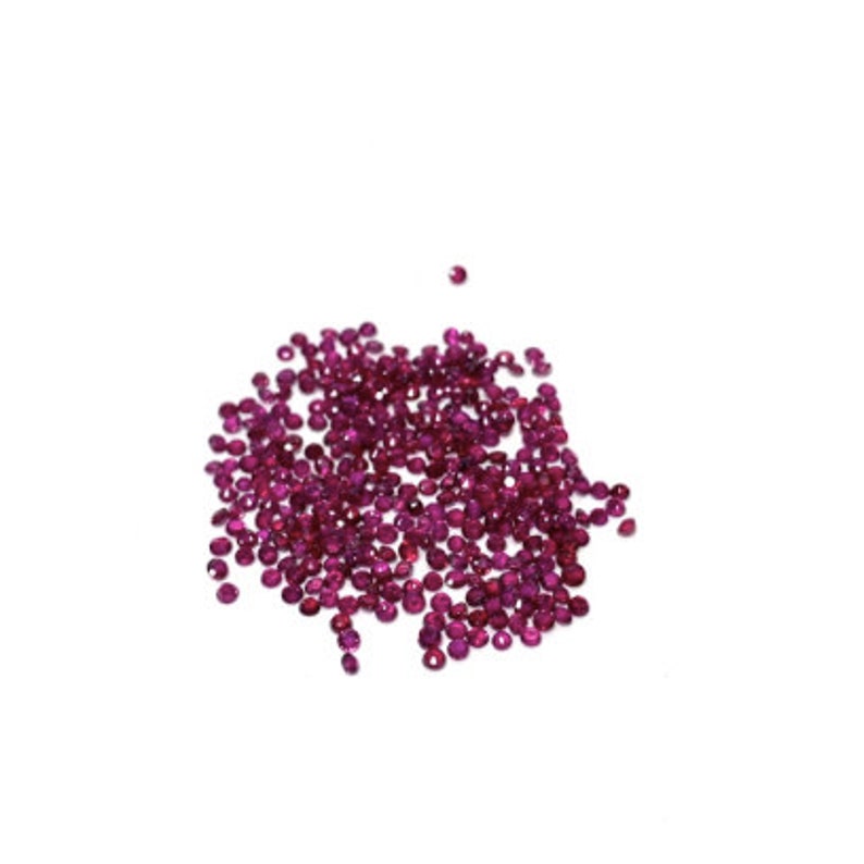 May include: A pile of small, round, ruby red gemstones.