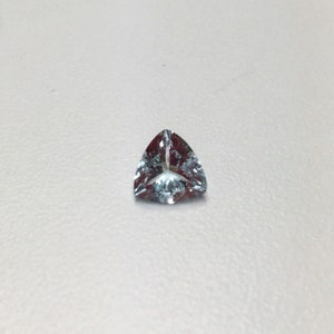May include: A light blue triangular gemstone with a faceted cut.