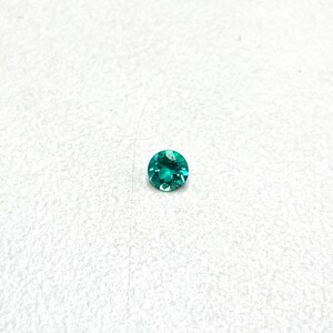May include: A round, bright green gemstone with facets.