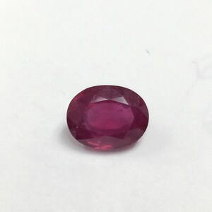 May include: A vibrant red oval-shaped gemstone with a faceted cut.