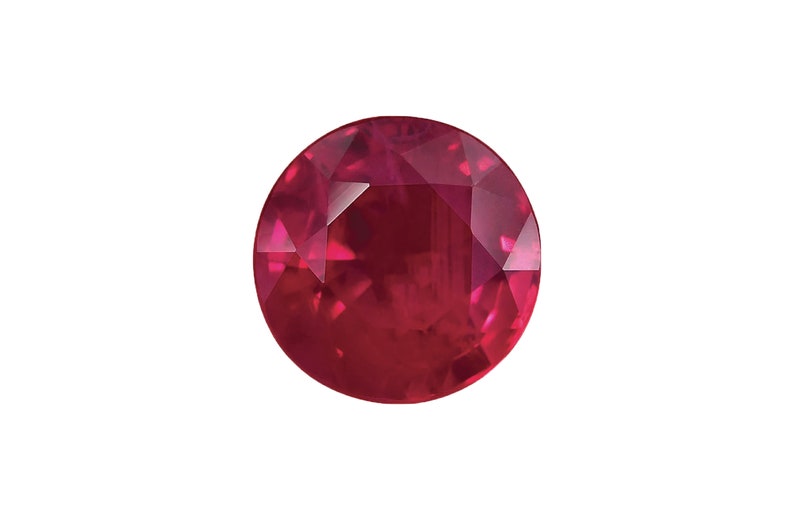 May include: A deep red ruby gemstone with a round cut and a faceted surface.