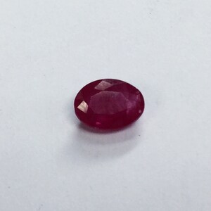 May include: A deep red oval-shaped gemstone with a faceted cut.