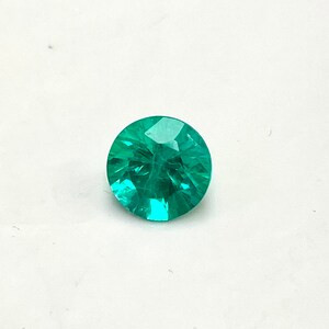 May include: A round, faceted, teal green gemstone.