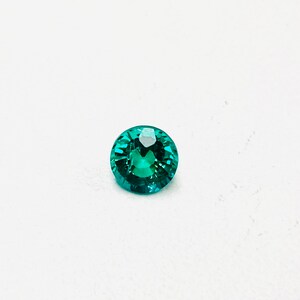 May include: A round, faceted, teal green gemstone.