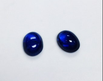 May include: Two oval-shaped blue gemstones, likely sapphires, are shown on a white background.