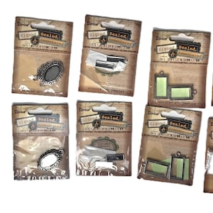 May include: Eight individual retail packages of metal jewelry pendants and bezels from the Signed, Sealed, Remembered collection. Each package contains various shapes including oval, rectangular, and square frames with metallic finishes and adhesive.