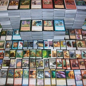 May include: A large collection of Magic: The Gathering cards, organized in rows and stacks. The cards feature various illustrations and text, including green, blue, and red colors.
