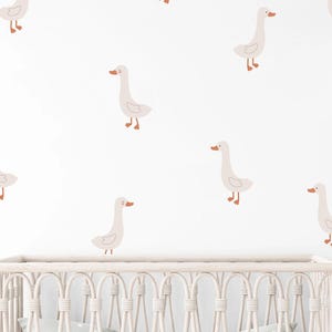 May include: A set of wall decals featuring multiple light beige geese with orange beaks and feet, arranged in a scattered pattern. Each goose is depicted in a simple, clean line art style, creating a repeating motif across the wall surface.