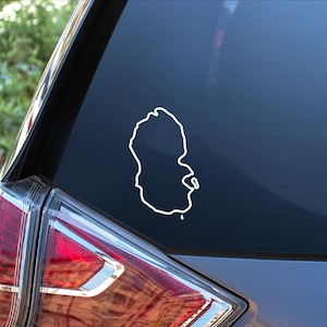 May include: A white outline of an island shape on a dark gray car window.
