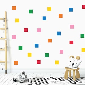 May include: A white wall decorated with colourful square stickers in various shades of red, orange, yellow, green, blue and pink. There is a wooden ladder, a small wooden chair with a black and white cushion, and a black and white patterned rug on the floor.
