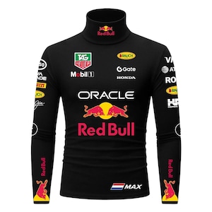 Puede incluir: Camiseta negra de manga larga con cuello alto con múltiples logotipos de patrocinadores y el logotipo de Red Bull. La camiseta incluye el texto "ORACLE" y "MAX". Las mangas muestran el logotipo de Red Bull y un gráfico de toro.