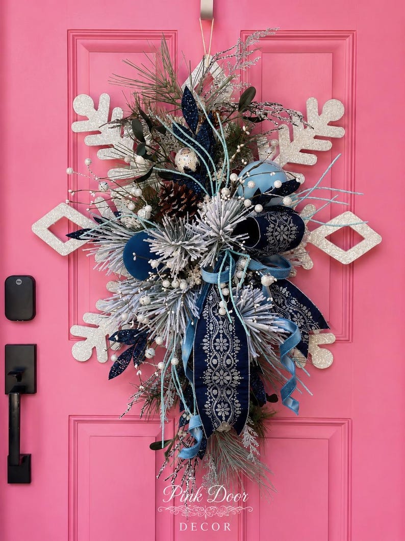 Christmas Snowflake Door Hanger — large silver glittered snowflake with navy and light blue ribbons, pine, white berries, and blue ornaments