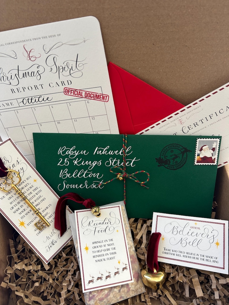 Pode incluir: Uma caixa de presente de Natal com um envelope verde endere&ccedil;ado a Robyn Inkwell, 25 Kings Street, Bellton, Somerset. A caixa cont&eacute;m uma chave de ouro, um pequeno saco de comida para renas, um sino de ouro e um cart&atilde;o que diz "Official Believers Bell".