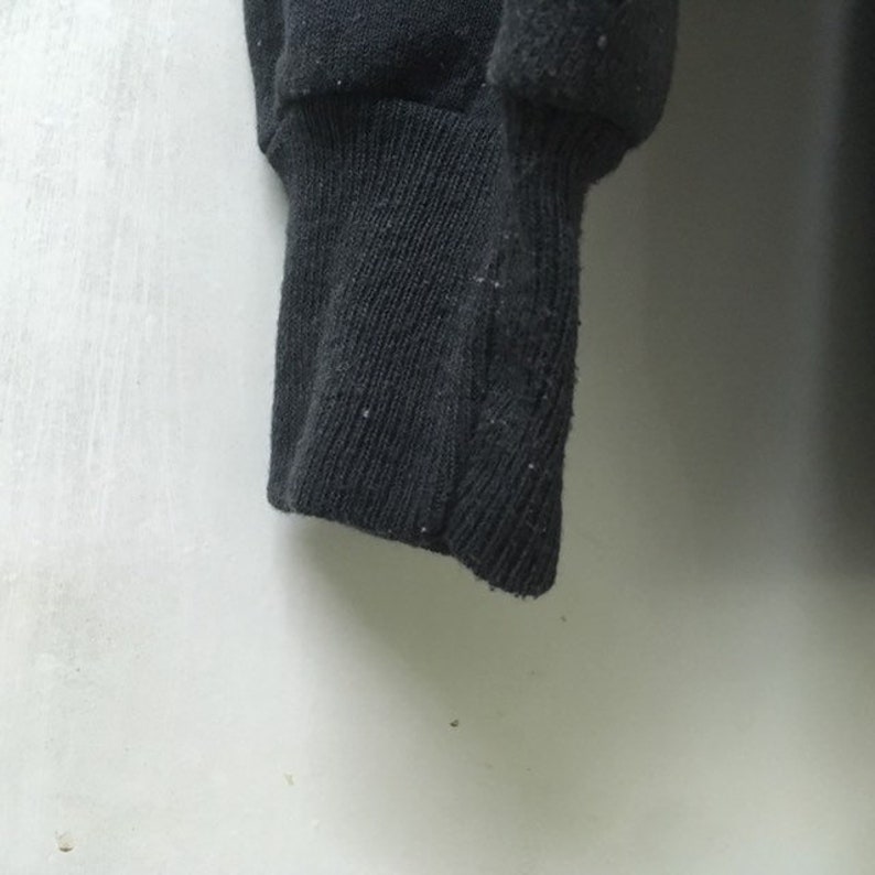 May include: Close-up of a black sweatshirt cuff. The cuff is made of a soft, knitted fabric.