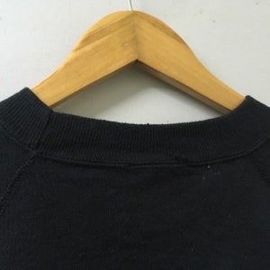 May include: Black sweatshirt with a ribbed neckline and raglan sleeves.