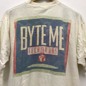 Peut inclure: T-shirt blanc avec un imprimé graphique bleu et rouge qui dit "BYTE ME TECHWORKS" avec une boîte rouge et une flèche blanche à l'intérieur.