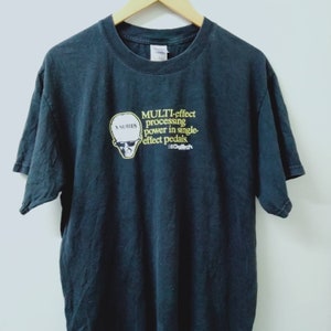 Op de afbeelding: Zwart T-shirt met een afbeelding van een cartoonhoofd met een zonnebril en de tekst "X-Series" erboven. De tekst "MULTI-effect processing power in single-effect pedals." staat onder het cartoonhoofd. De tekst "DigiTech" staat onder de tekst "effect pedals."