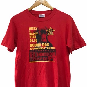 May include: Red t-shirt featuring a graphic of a dog and the text "Lucky & Happy Star 20.00 Hound Dog Concert Tour" and "HD Hound Dog Lucky & Happy Star 20".