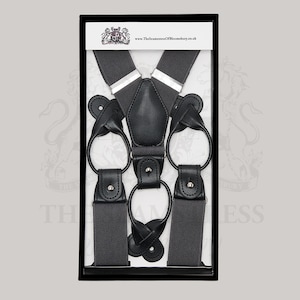 Puede incluir: Tirantes gris oscuro con detalles de cuero negro, presentados en una caja negra. Los tirantes presentan un dise&ntilde;o cl&aacute;sico con presillas de cuero y ajustadores met&aacute;licos. El producto se muestra sobre un fondo blanco.