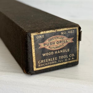 Puede incluir: Un taladro de empuje Greenlee vintage en su caja original. La caja es de color marr&oacute;n oscuro con una etiqueta dorada que dice "Greenlee Push Drill Automatic Wood Handle". La etiqueta tambi&eacute;n incluye el texto "Greenlee Tool Co. Rockford, Ill. U.S.A."