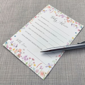Baby Advice Baby shower game card featuring a pink, yellow, Lilac and peach wildflower design on a white background. Shown alongside a pen