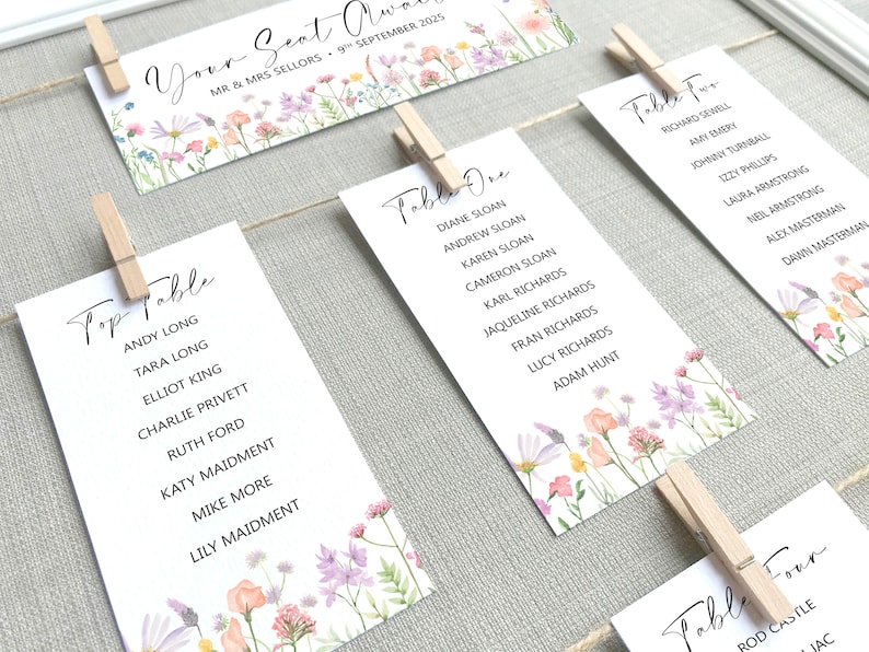 Lilac, Pink, Peach and Yellow Wildflower Print Wedding Seating Plan Cards shown pegged on string in a white frame and grey linen background