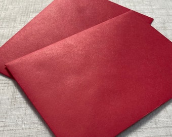 May include: Two red envelopes, one on top of the other, with a textured surface.